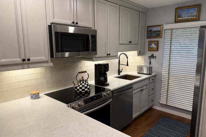 The starting photo: a galley kitchen with pale gray cabinets, white counters and a subway tile backsplash.