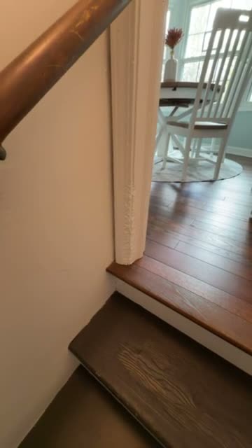 A frame from the repair video: white door casing at the foot of a staircase, scratched and chewed along its lower edge.